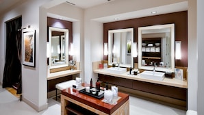 Un baño moderno con dos lavamanos, espejos grandes y un mueble de tocador con artículos de aseo.