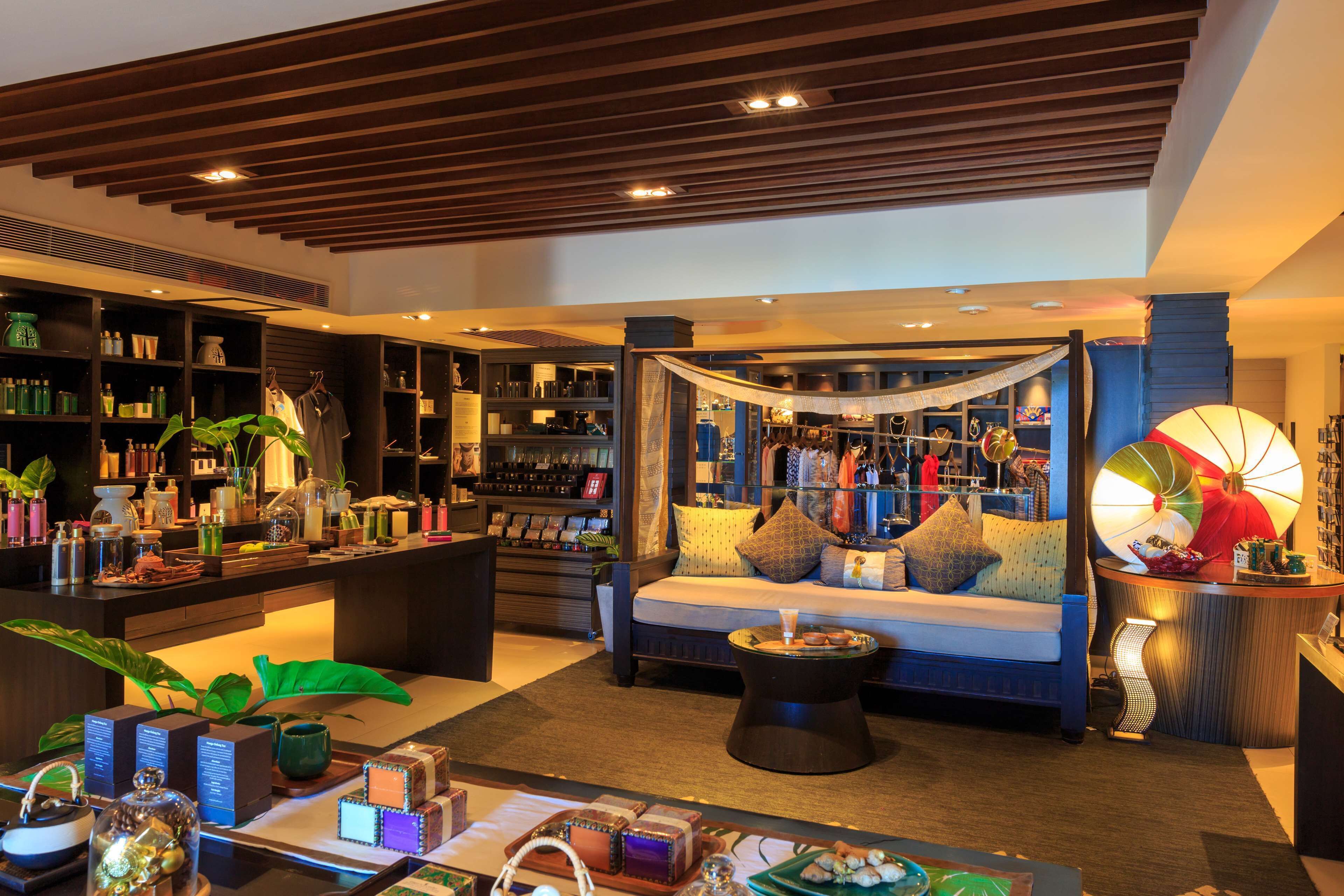 A well-lit hotel lobby with a seating area, a bookshelf, and a reception desk.