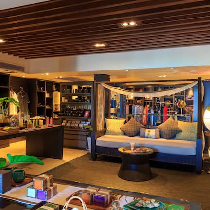A well-lit hotel lobby with a seating area, a bookshelf, and a reception desk.
