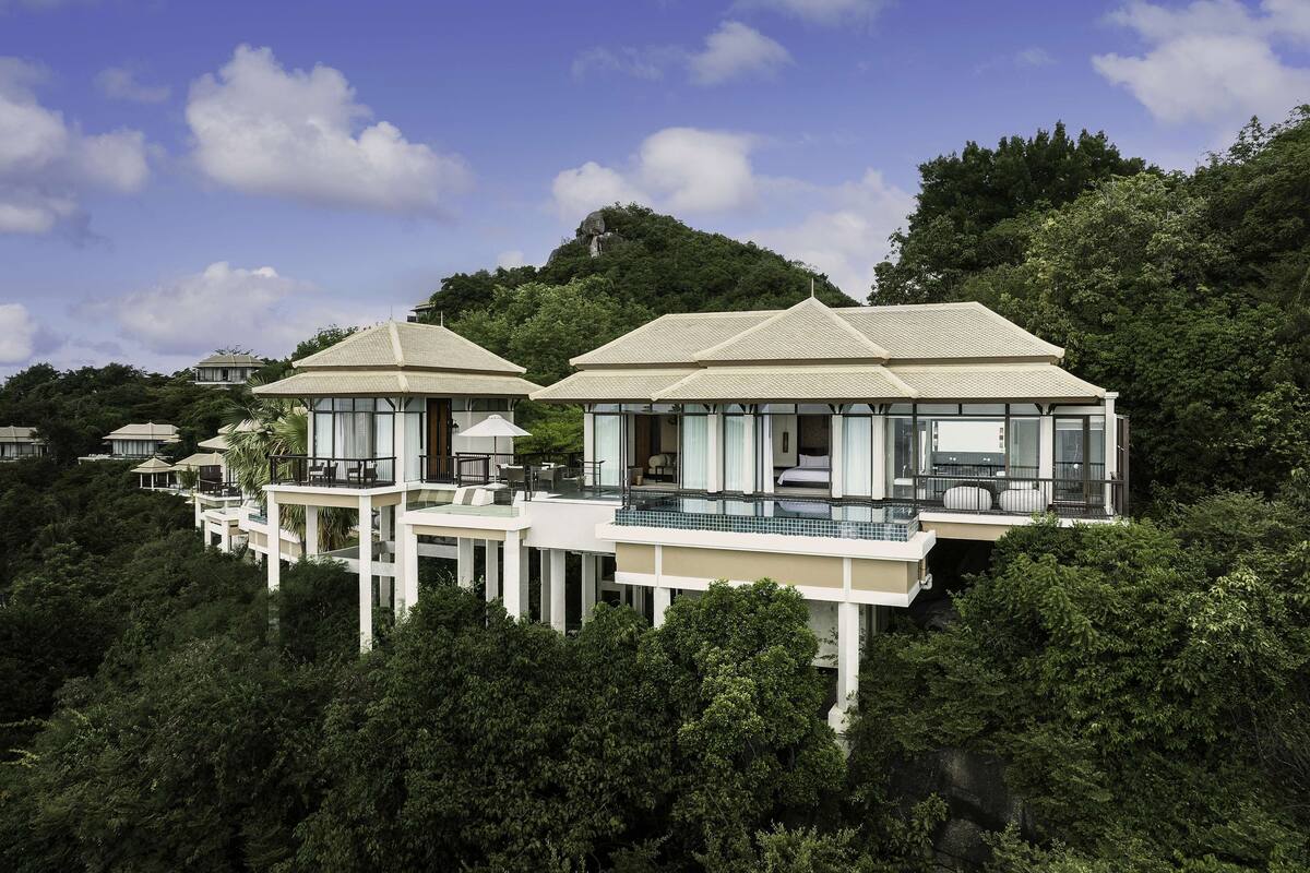 A resort with multiple bungalow-style buildings, each featuring a balcony and a pool.