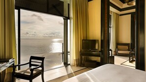 A hotel room with a large bed, a desk, a chair, a TV, and a balcony with a view of the water. - Banyan Tree Samui (Koh Samui)