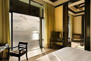 A hotel room with a large bed, a desk, a chair, a TV, and a balcony with a view of the water. - Banyan Tree Samui (Koh Samui)