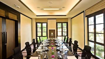 A conference room with a long table, chairs, and a projector screen.