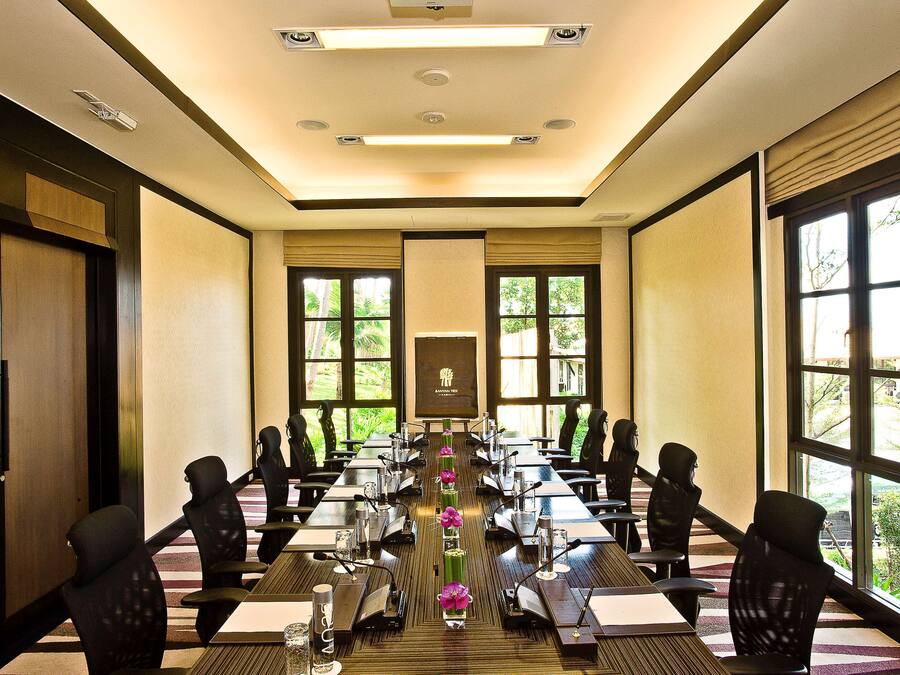 A conference room with a long table, chairs, and a projector screen.