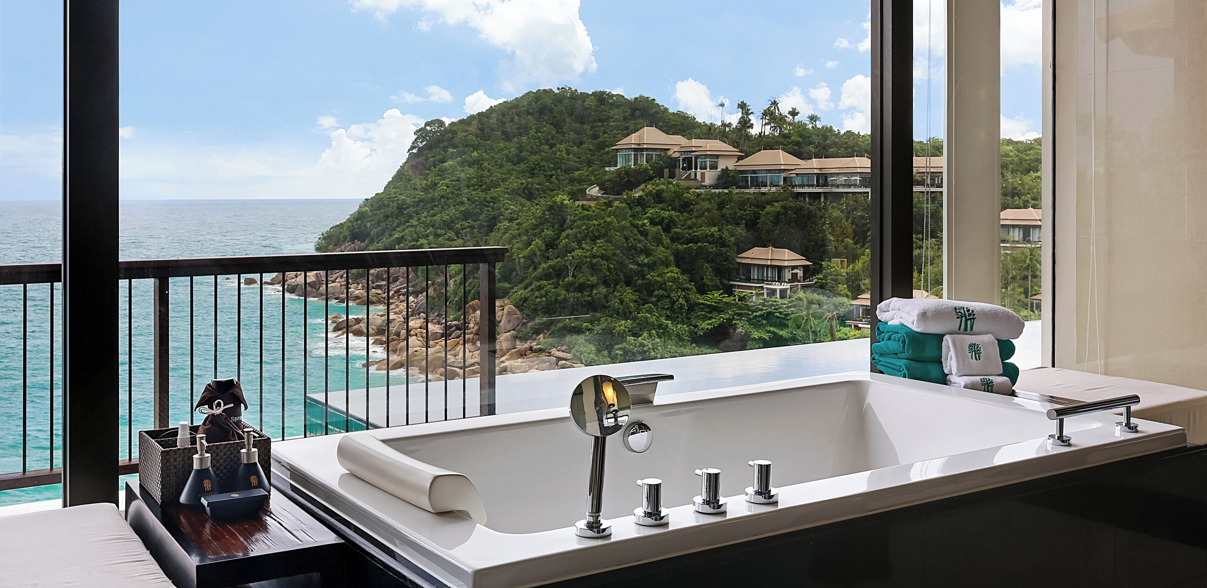 Un baño con un ventanal grande con vistas al litoral, una bañera e un lavabo con accesorios modernos.