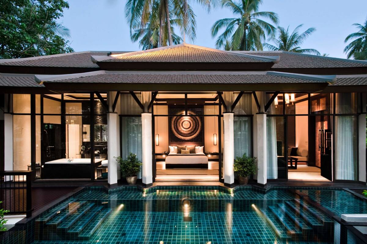A modern resort with a large swimming pool, a spa area, and a well-lit bedroom with a circular wall design.