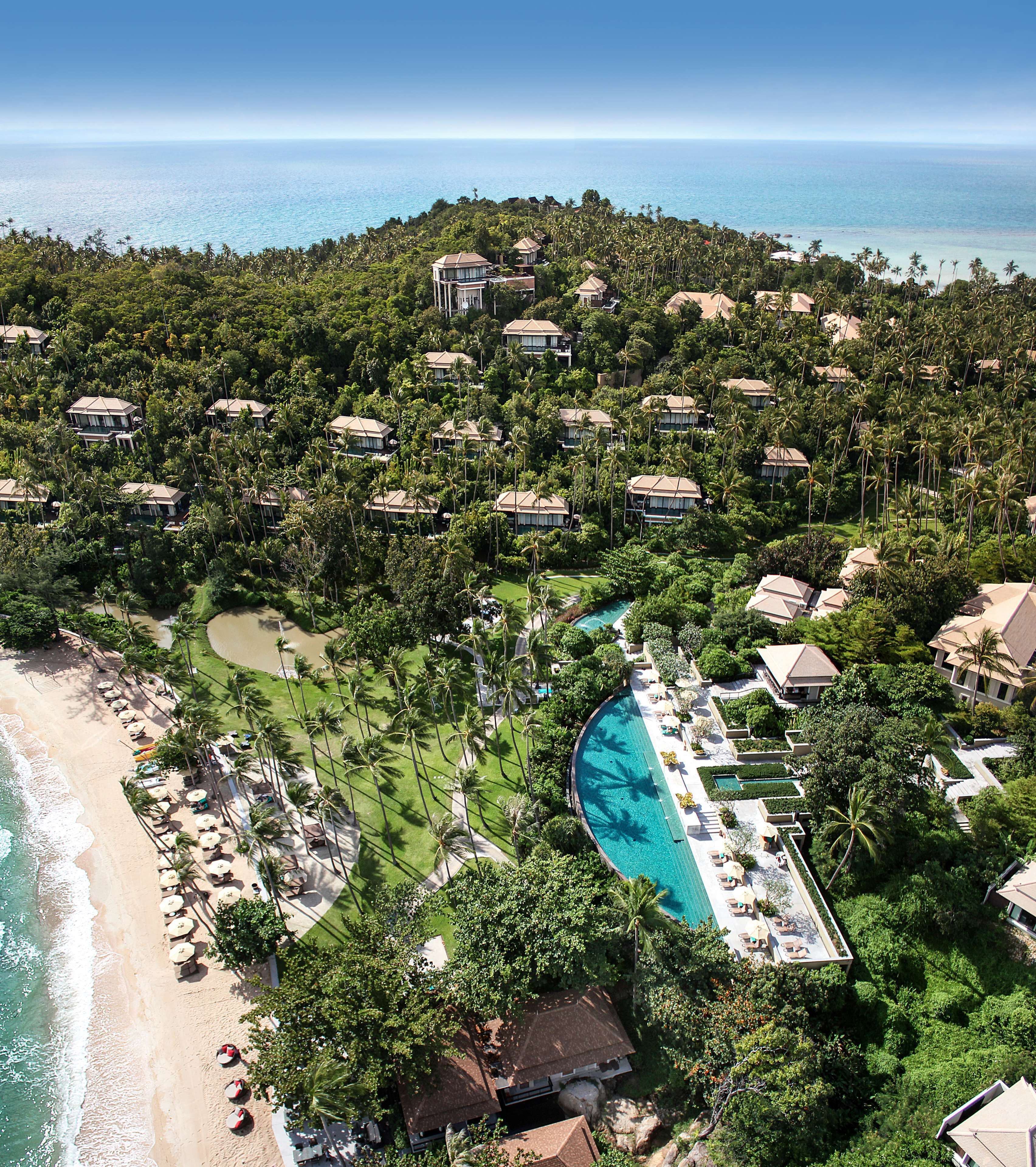 Vista aérea de un complejo turístico con varias cabañas tipo bungalow, una piscina central y acceso a la playa.