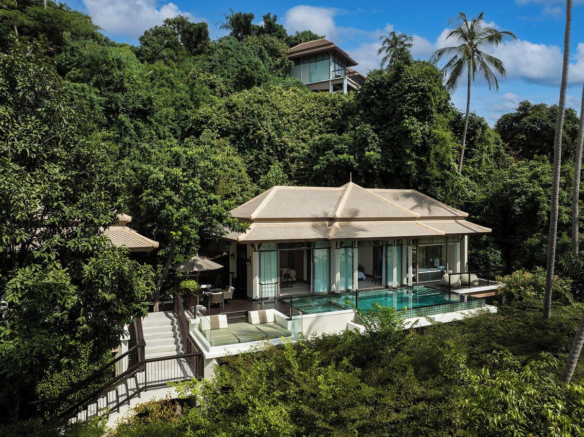 A resort with a pool, surrounded by lush greenery and a hilltop location.
