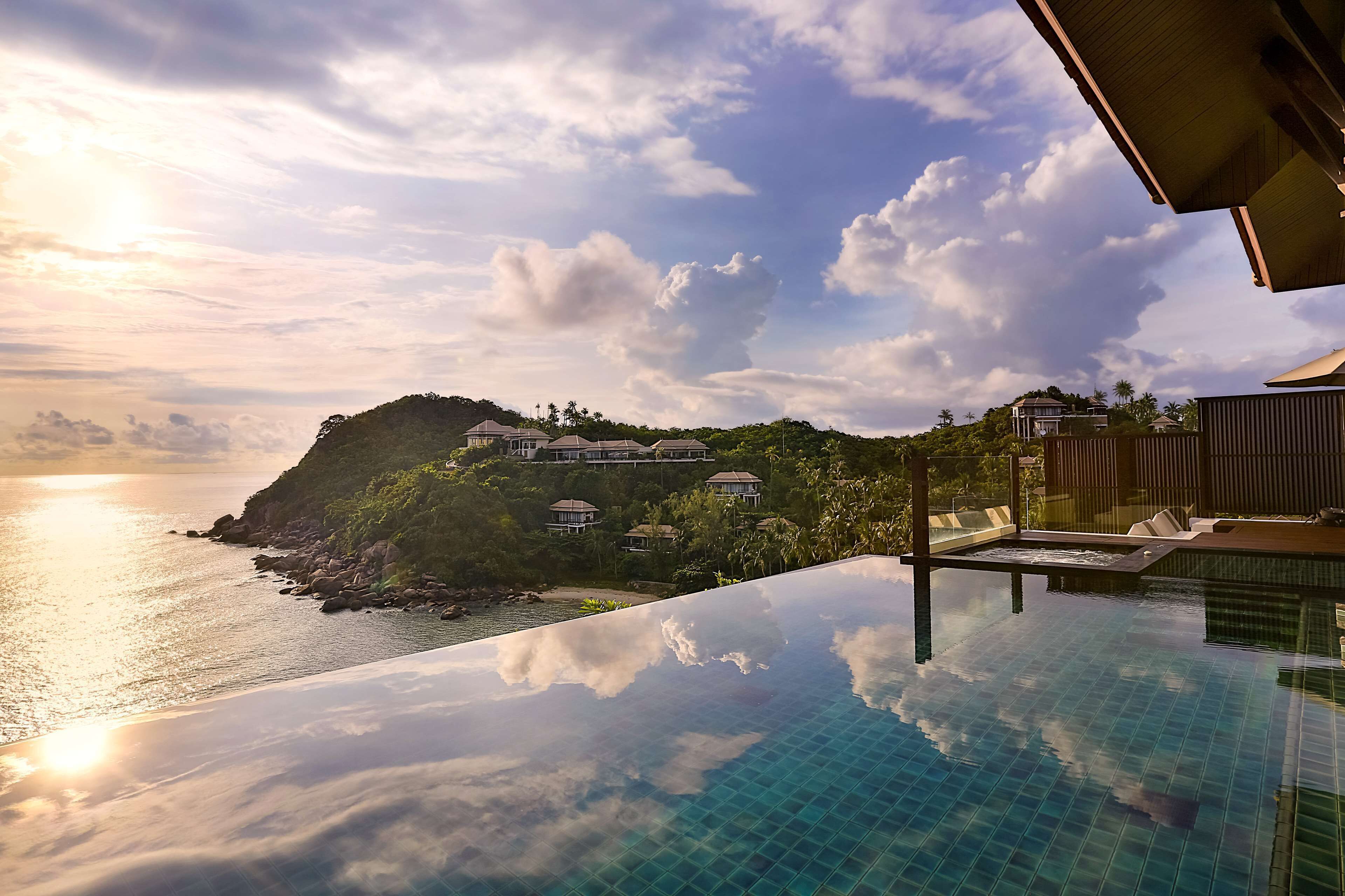 Una piscina infinita con vistas claras al océano y un paisaje montañoso.