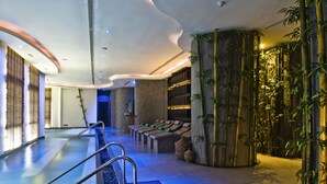 A modern indoor pool area with a curved ceiling, seating along the walls, and bamboo plants. - Banyan Tree Samui (Koh Samui)