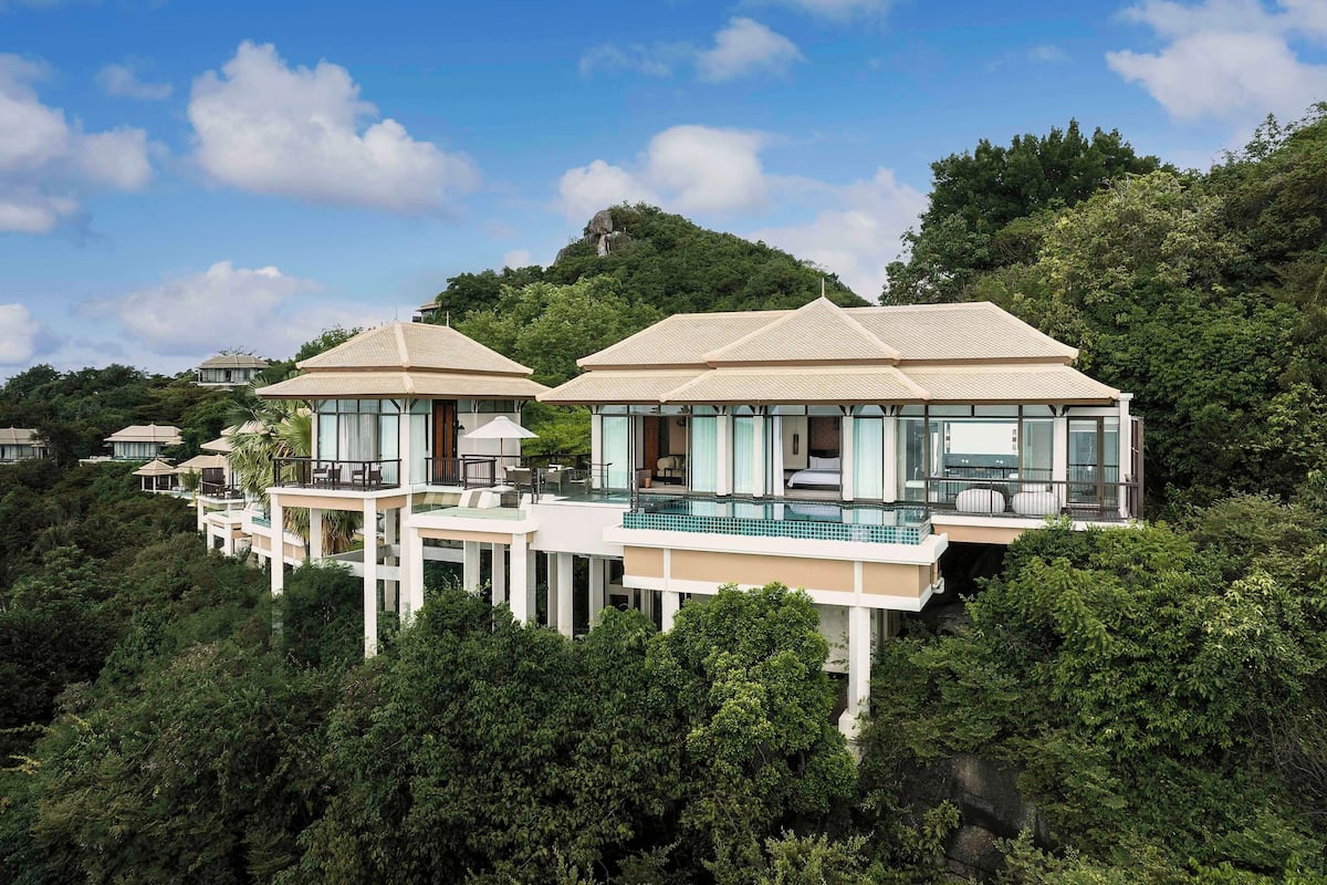 A resort with multiple bungalow-style buildings, each featuring a balcony and a pool.