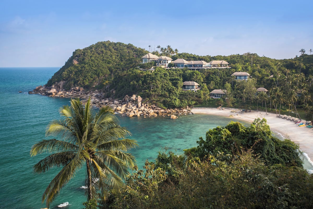 Une propriété située sur la côte, comprenant plusieurs villas sur une colline surplombant une plage.