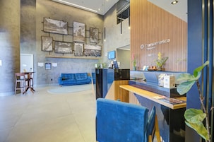 A modern reception area with a blue sofa, a reception desk, and a wall with framed pictures.