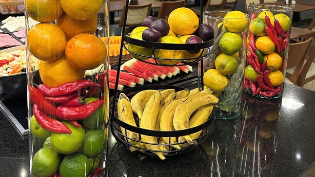 Vruchtenpresentatie met sinaasappels, limoenen, bananen en watermeloenen in doorzichtige bakken.