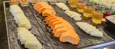 Un buffet proposant une variété de plats, notamment des viandes et des fruits coupés en tranches.