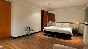 Habitación de hotel con una cama grande, mesitas de noche, una silla y suelo de madera.