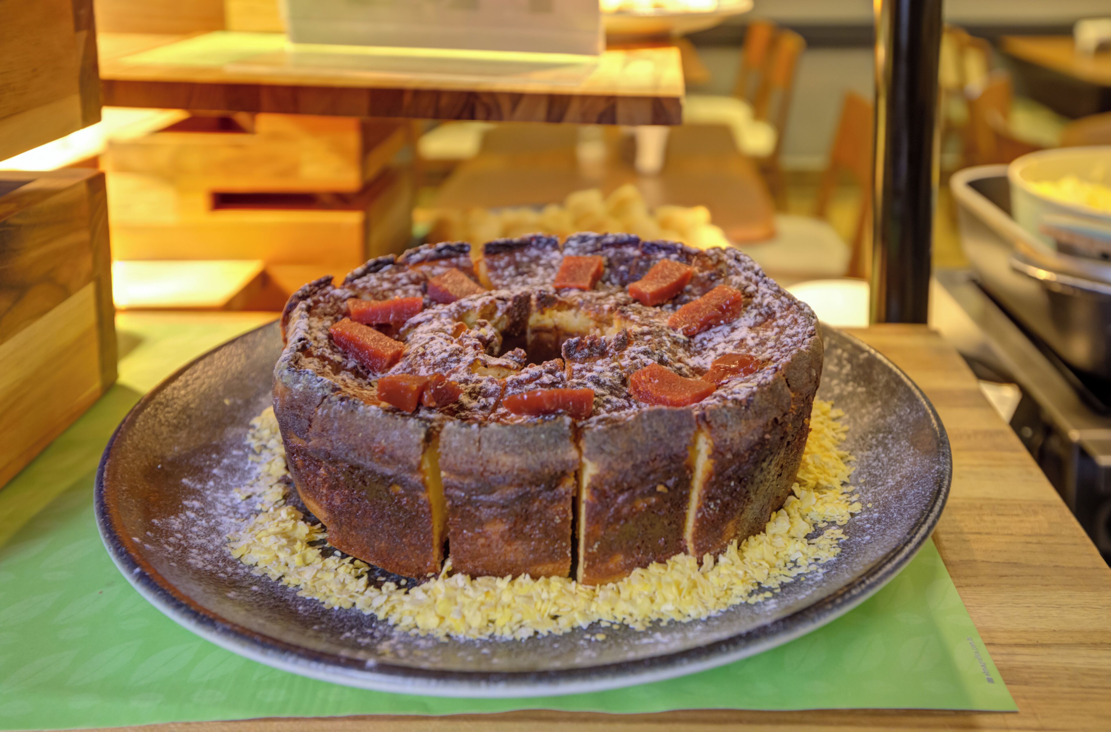 A round cake with fruit pieces on a plate, placed on a table.