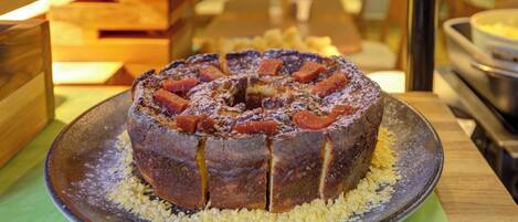 A round cake with fruit pieces on a plate, placed on a table.