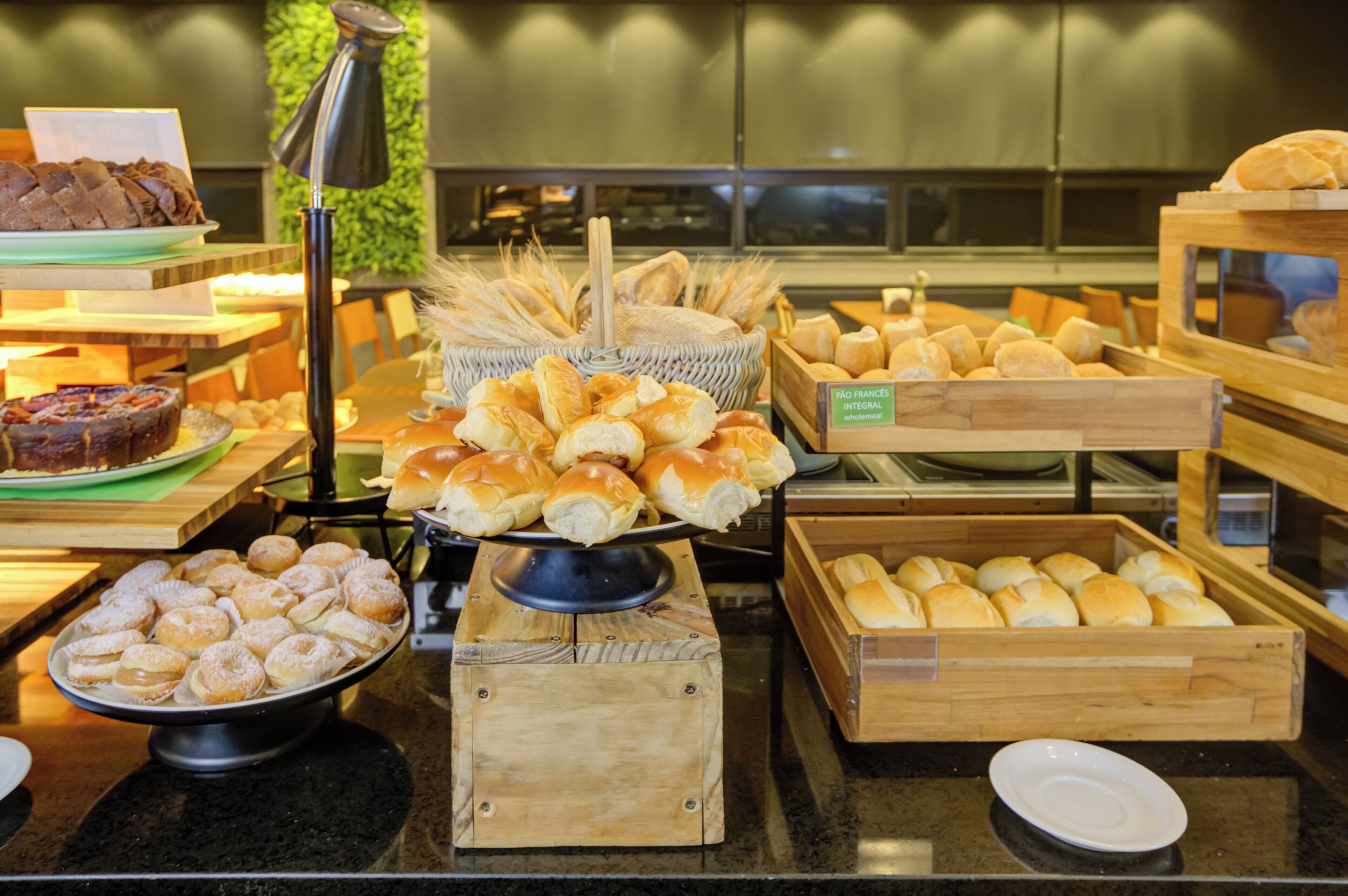 A buffet with various baked goods including bread, pastries, and rolls.