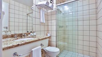 Un baño con lavamanos, inodoro y cabina de ducha de vidrio.