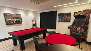 Een kamer met een pooltafel, een rode tafel en een game stoel.