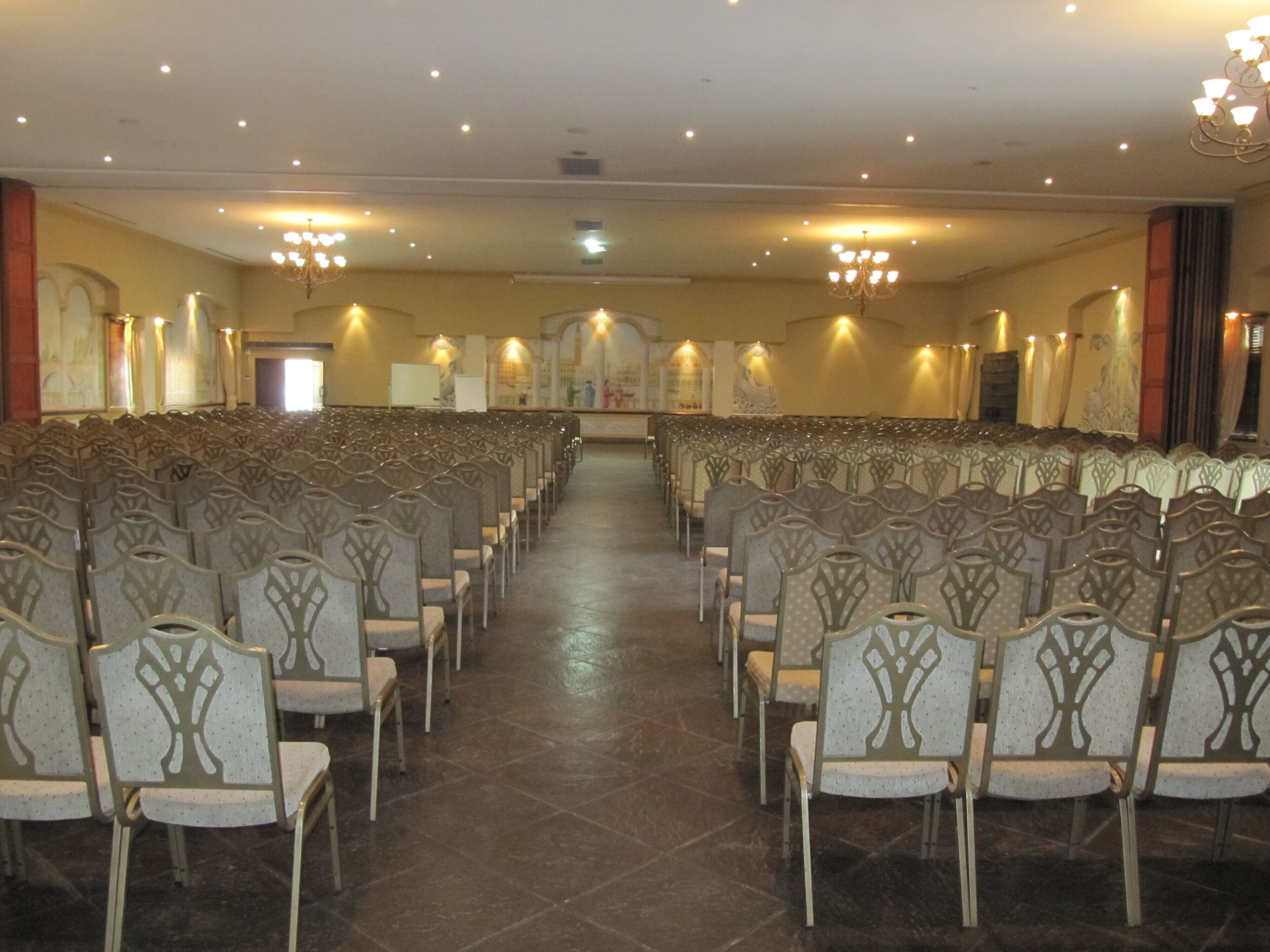 A conference room with rows of chairs and a stage at the front.