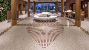 Un vestíbulo amplio con una zona de estar central, grandes pilares de madera y un diseño de suelo con motivos.