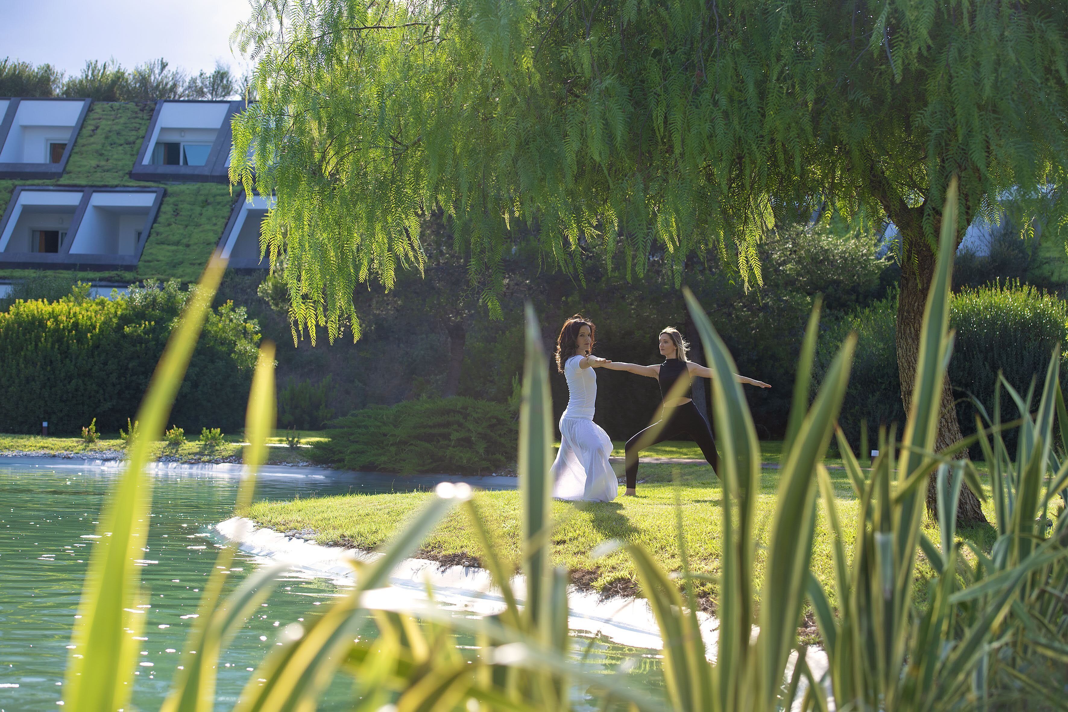 Une cérémonie de mariage au bord d’un lac, avec un bâtiment moderne en arrière-plan.