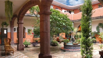 Relax in a serene courtyard surrounded by lush greenery and a central fountain.