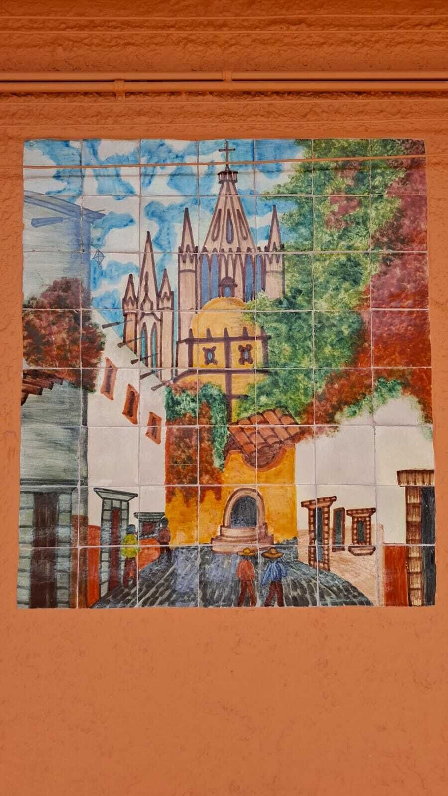 A mosaic with a church, a yellow building, and a street scene.