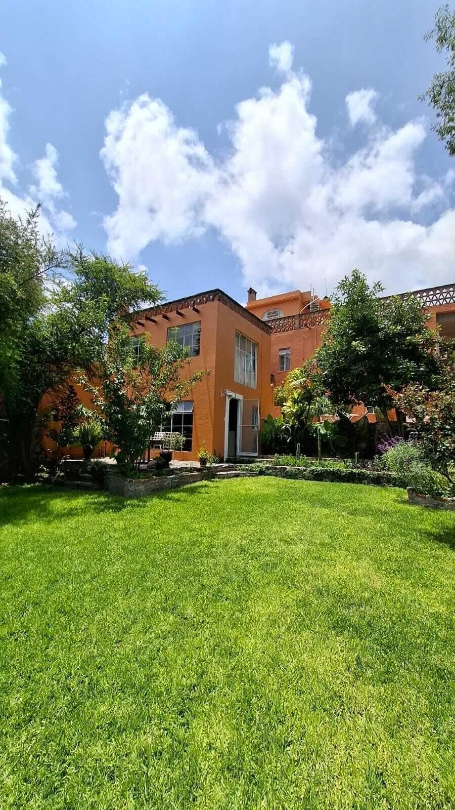 Un edificio con techo plano, un amplio jardín y cielo despejado.