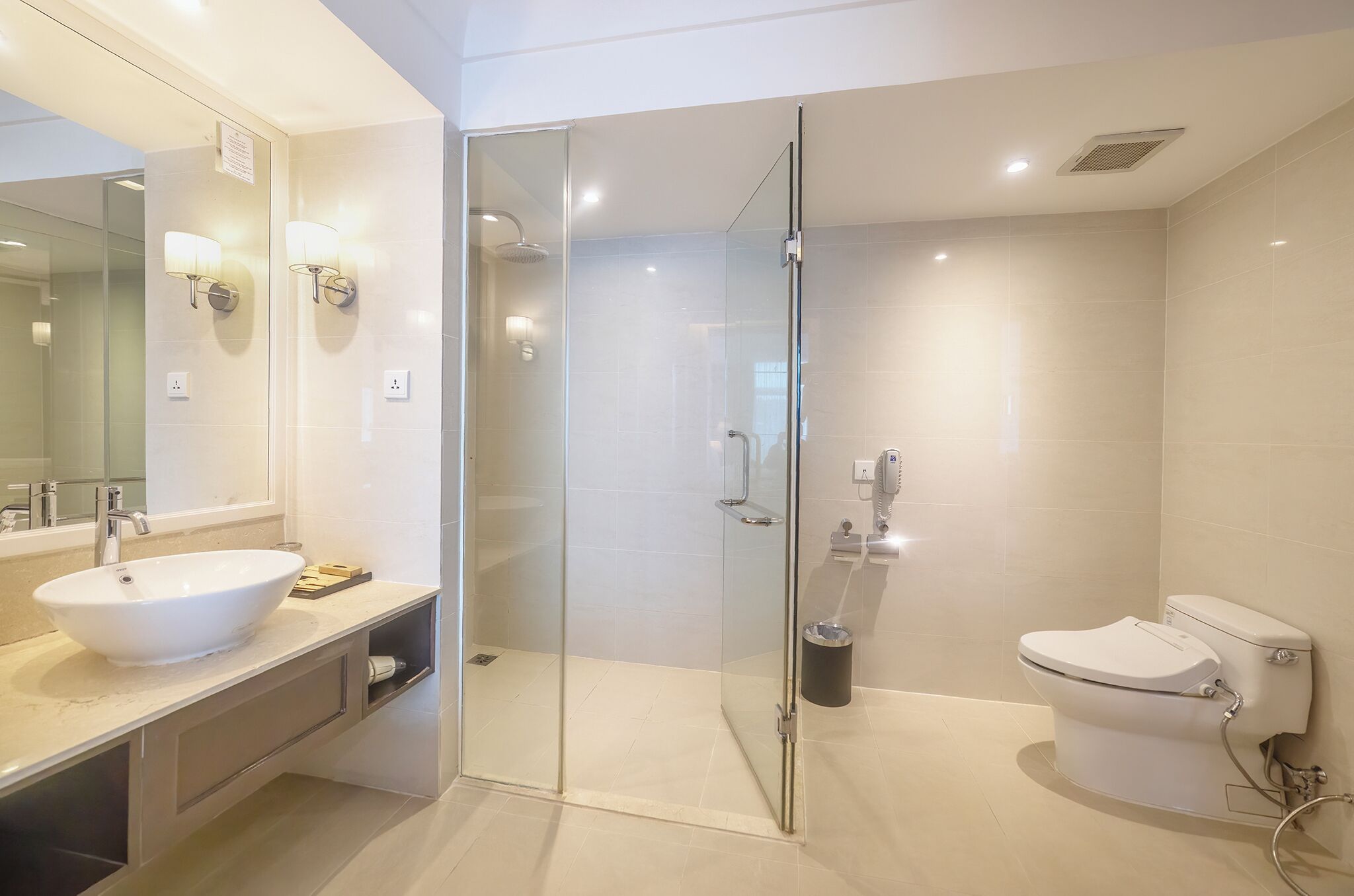 A modern bathroom with a glass-enclosed shower, a white sink, and a toilet.