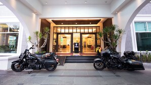 Entrada moderna de hotel com duas motocicletas estacionadas.