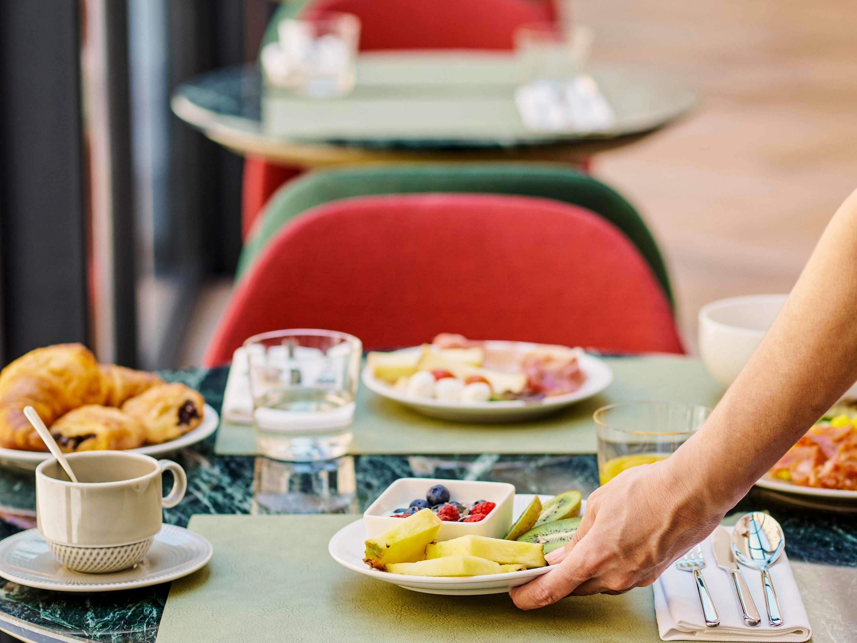 Desayuno con cruasanes, fruta y una taza sobre una mesa.