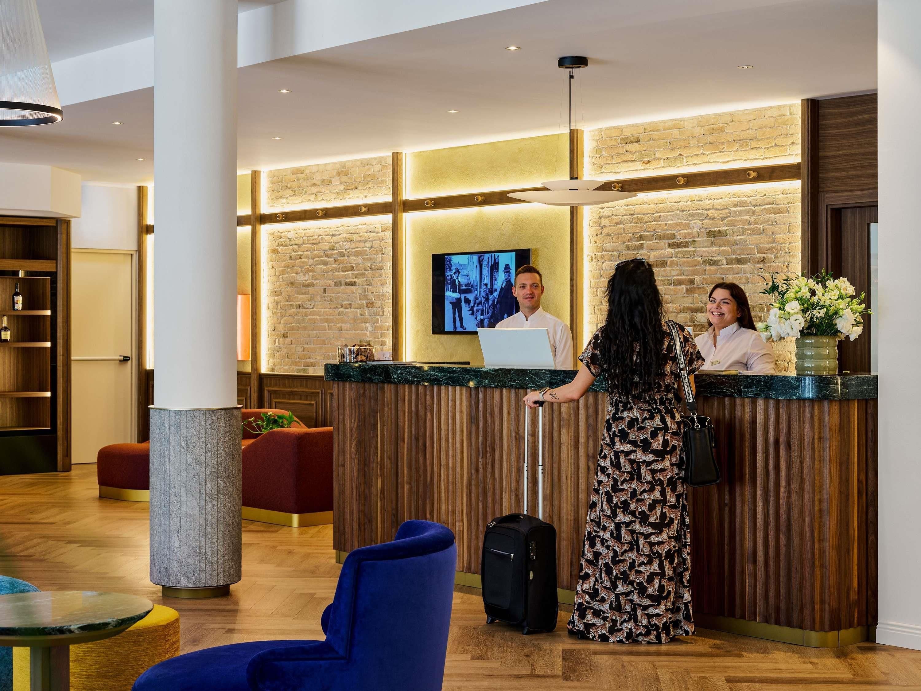 A hotel reception area with a wooden reception desk, a television, and a modern interior design.