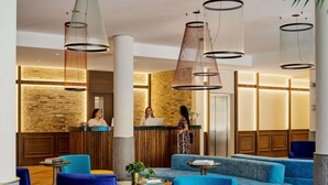 A hotel lobby with blue seating, a reception desk, and a brick wall. - Hotel Giacomo Morra Alba - Handwritten Collection (Alba)