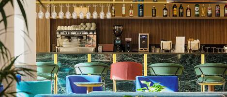 Zona de bar con asientos, una máquina de café y una vitrina de vinos.