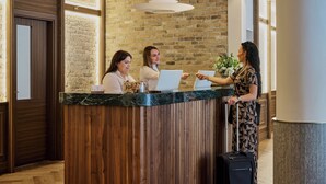 A reception desk with a wooden panel design, a brick wall, and a hanging light fixture.
