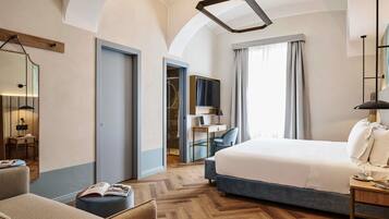 Una habitación de hotel moderna con una cama grande, un escritorio con una computadora portátil, una silla y un pequeño rincón de descanso con un libro.
