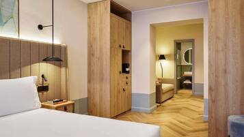 Een hotelkamer met een bed, nachtkastje, lamp, garderobe en uitzicht op de badkamer.