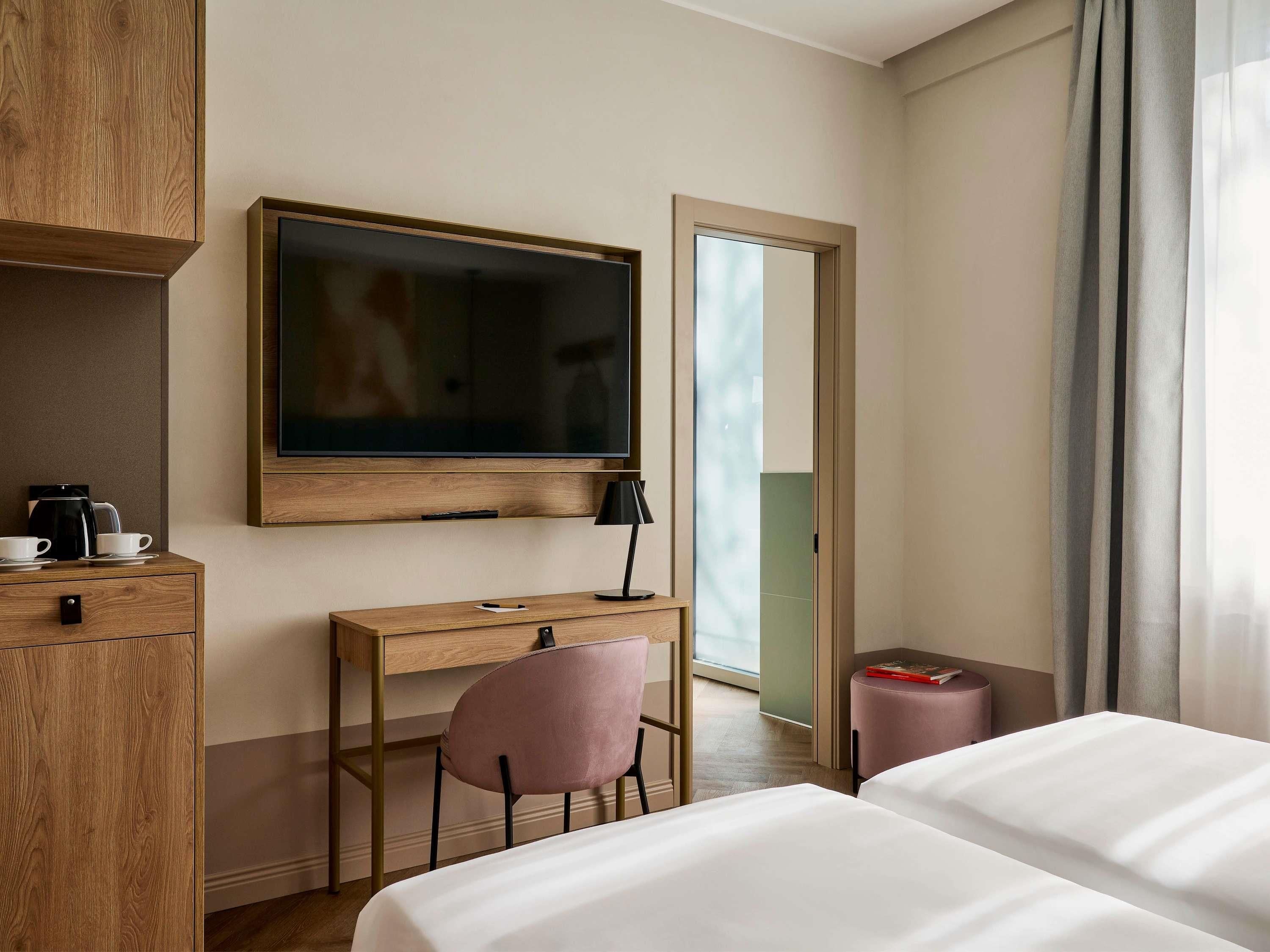 Une chambre d’hôtel équipée d’un lit, d’un bureau, d’une chaise, d’une télévision et d’une machine à café.