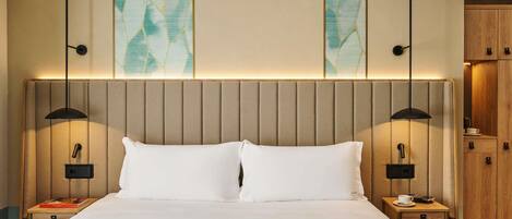 Una habitación de hotel con una cama grande, dos mesitas de noche, un armario de madera y arte abstracto en la pared.