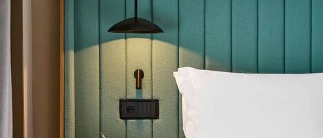 A neatly made bed with a white pillow and a teal headboard.
