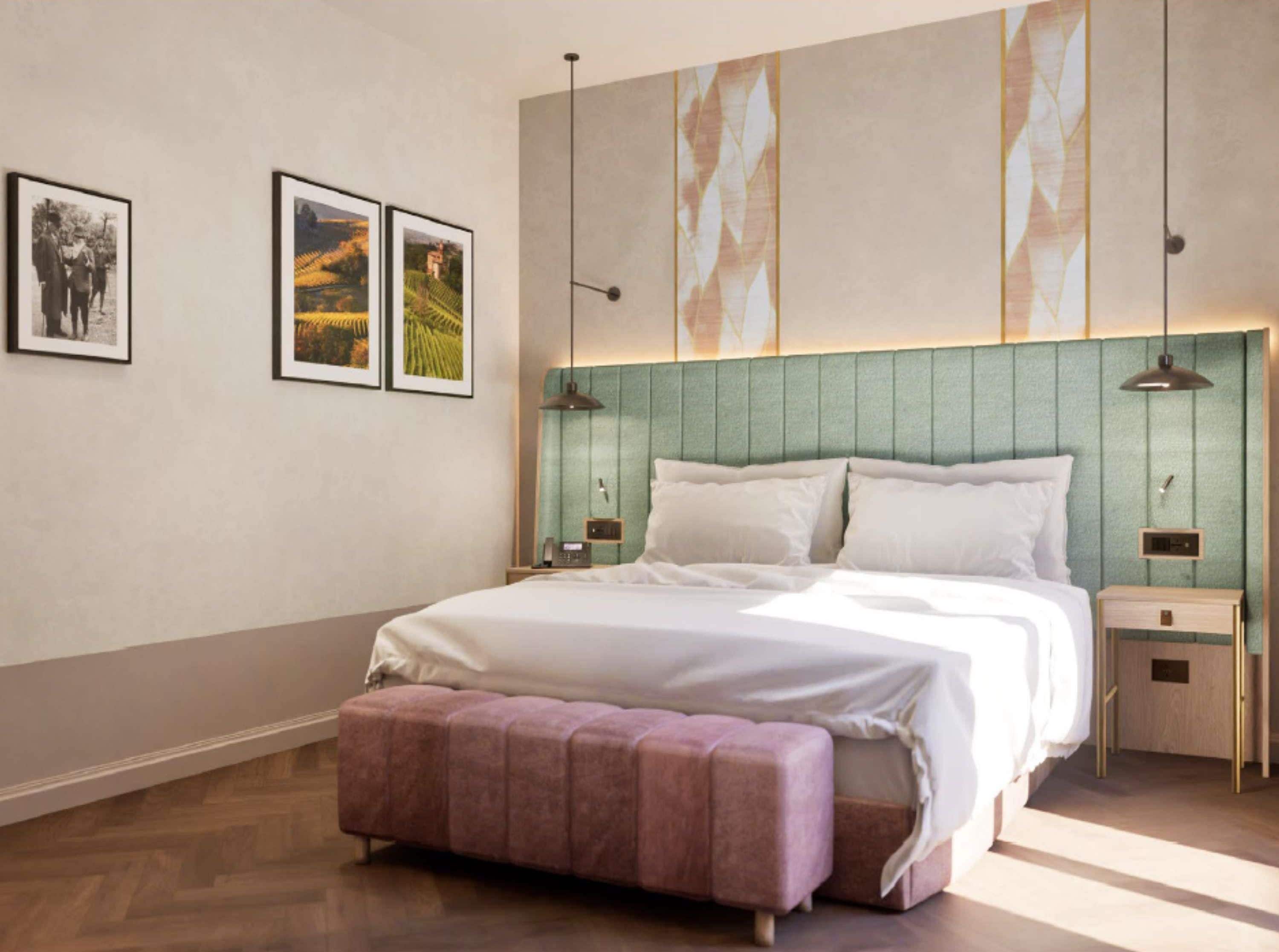 Un dormitorio moderno con una cama grande, un banco y dos mesitas de noche. Hay cuadros enmarcados en la pared.