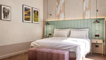 Un dormitorio moderno con una cama grande, un banco y dos mesitas de noche. Hay cuadros enmarcados en la pared.