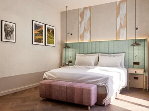 Un dormitorio moderno con una cama grande, un banco y dos mesitas de noche. Hay cuadros enmarcados en la pared.