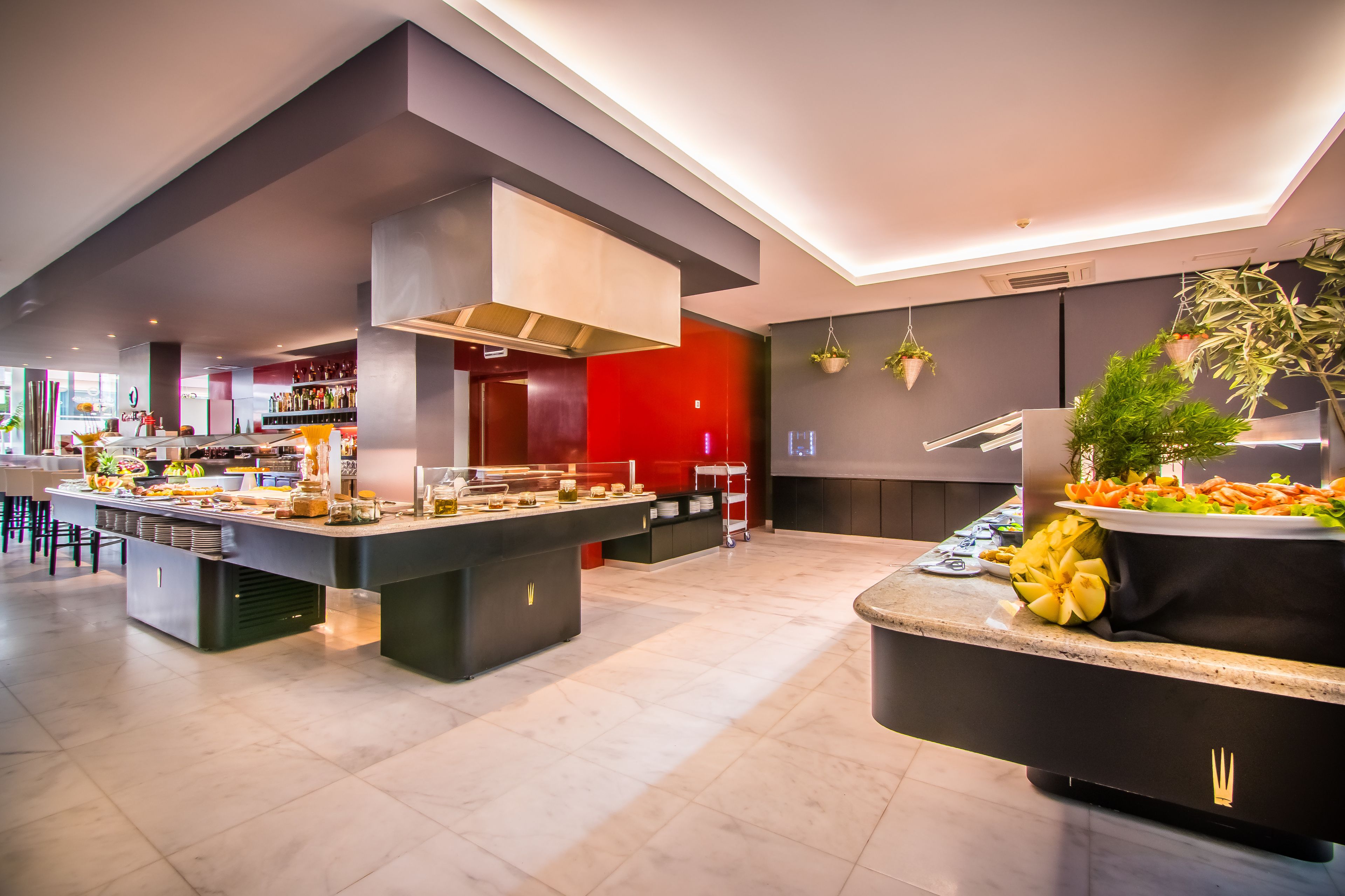 Une cuisine moderne dotée d’un îlot central, d’un mur d’accent rouge et d’une variété de produits alimentaires exposés.