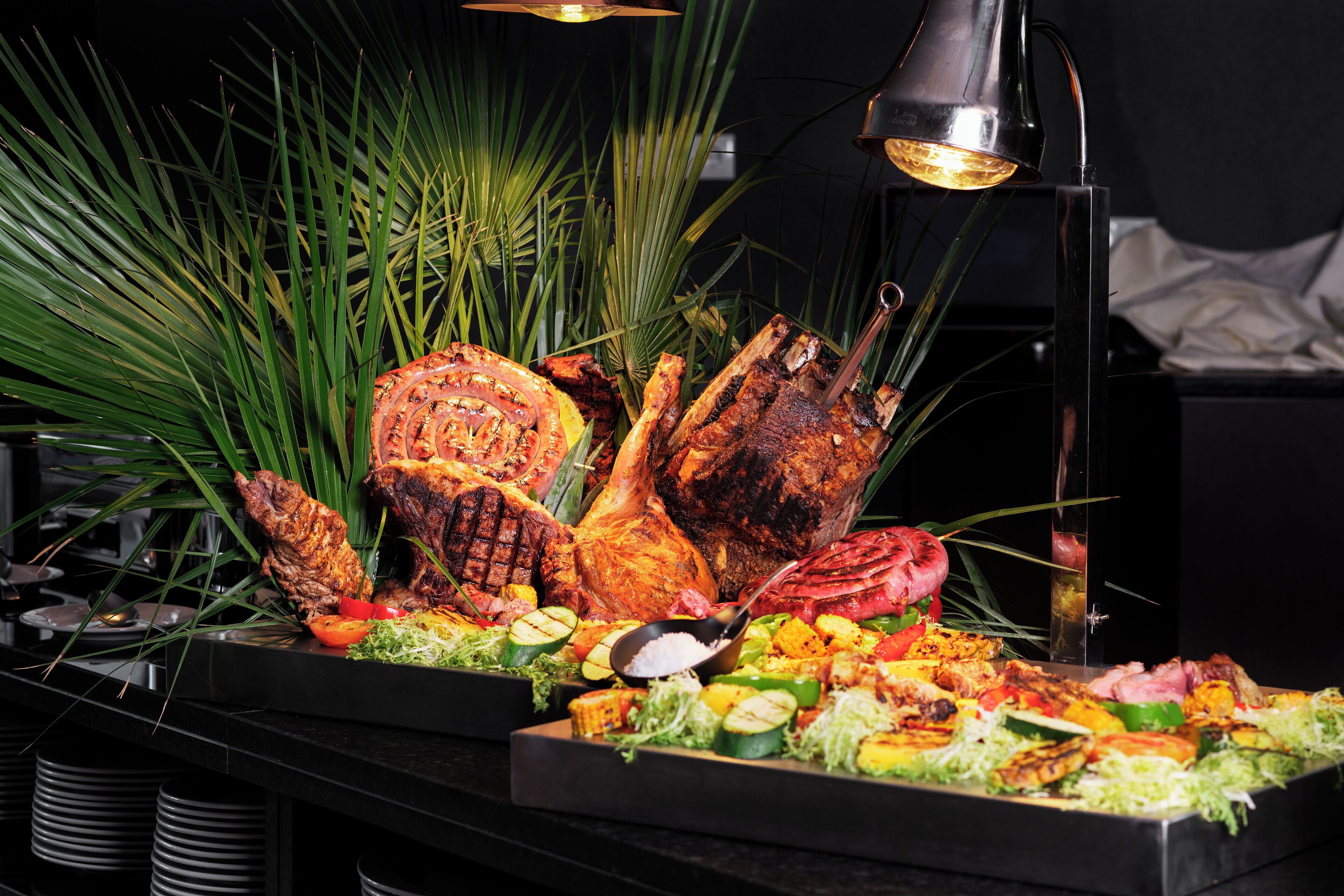 A buffet with grilled meats, vegetables, and a variety of dishes.