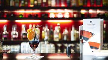Barmiljø med et glas drik, en menu og hylder med flasker i baggrunden.