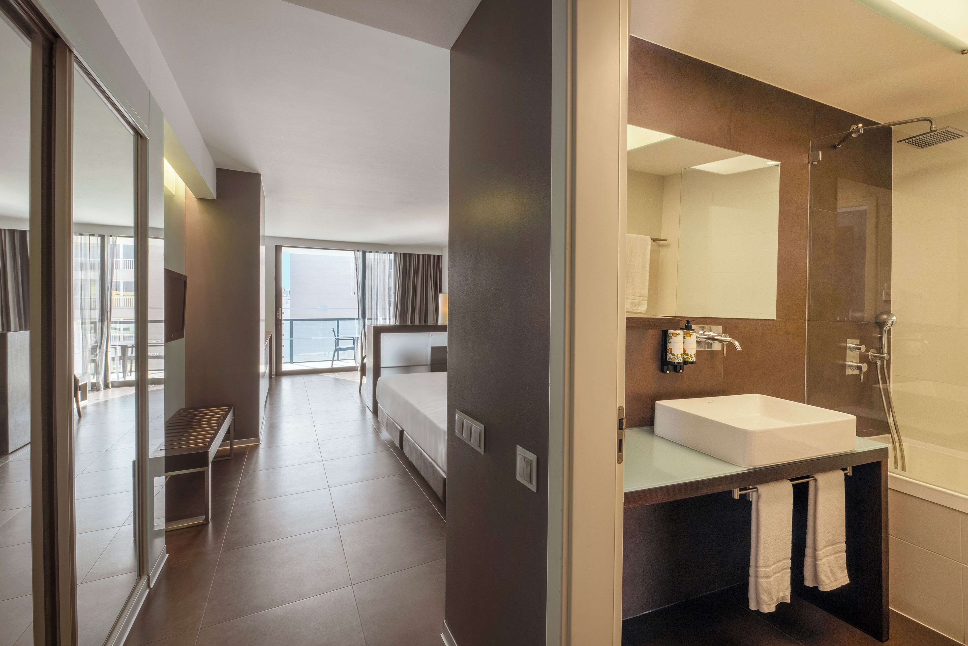 A modern bathroom with a large mirror, a white sink, and a shower.